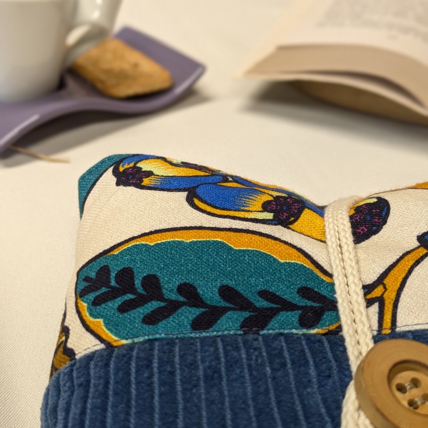 Zoom sur les finitions d'une pochette à livre broché, velours côtelé bleu indigo et coton imprimé