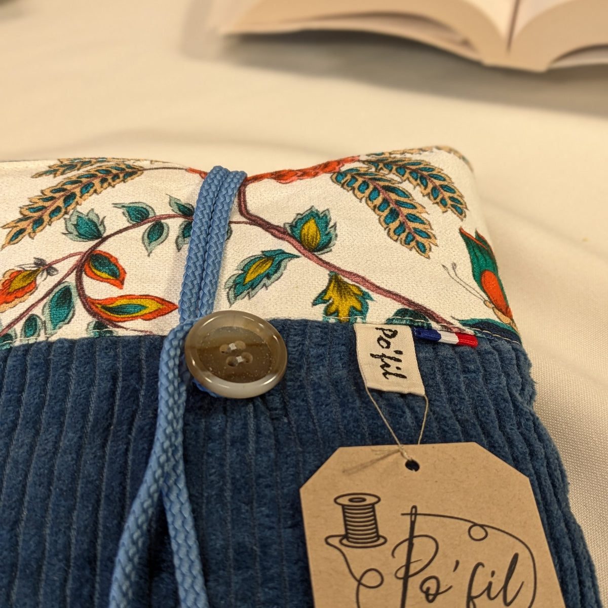 Zoom sur les finitions d'une pochette à livre de poche, velours côtelé indigo et coton imprimé