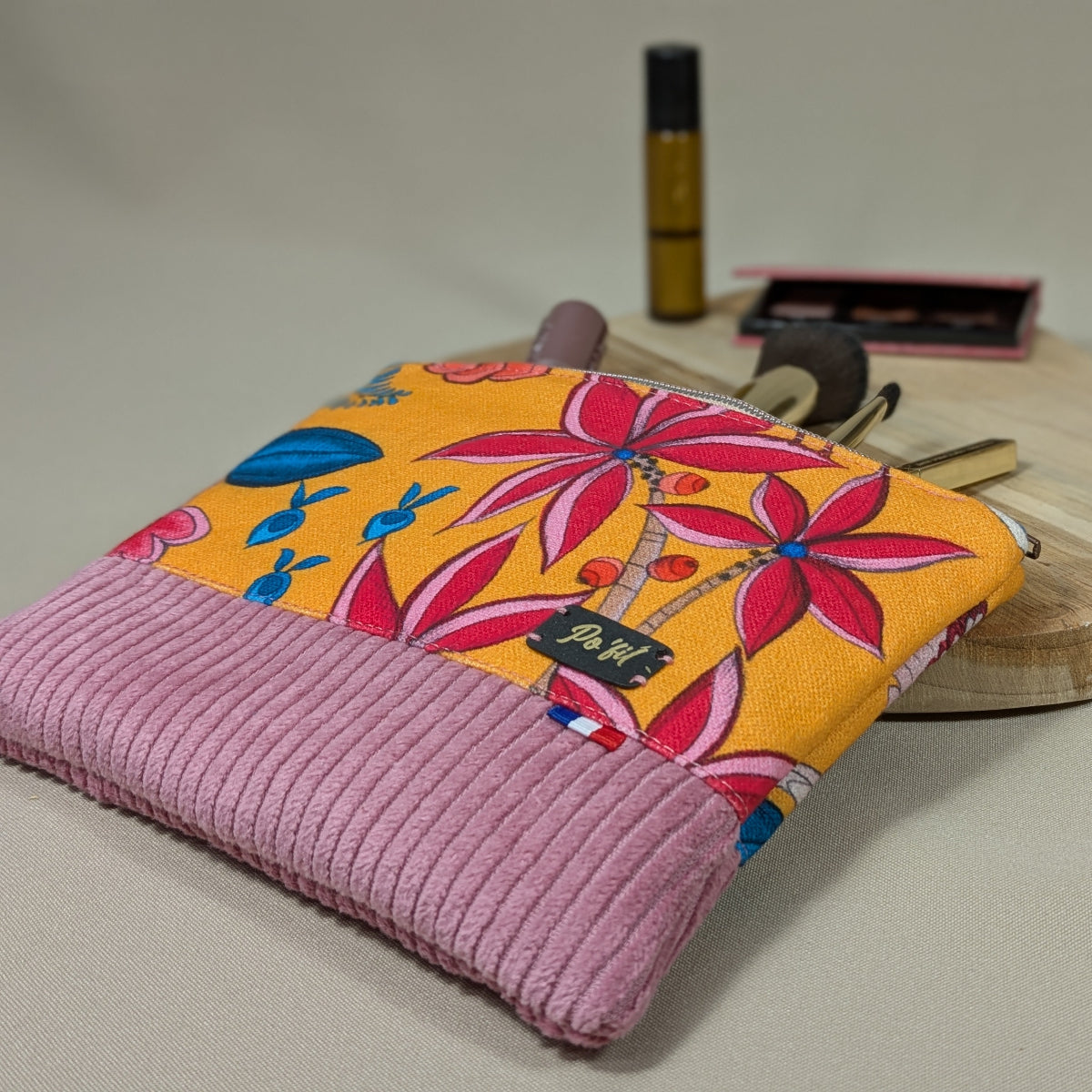 Sa taille est idéale pour être glissée dans un sac. Zoom sur les motifs floraux colorés sur fond orangé du coton imprimé