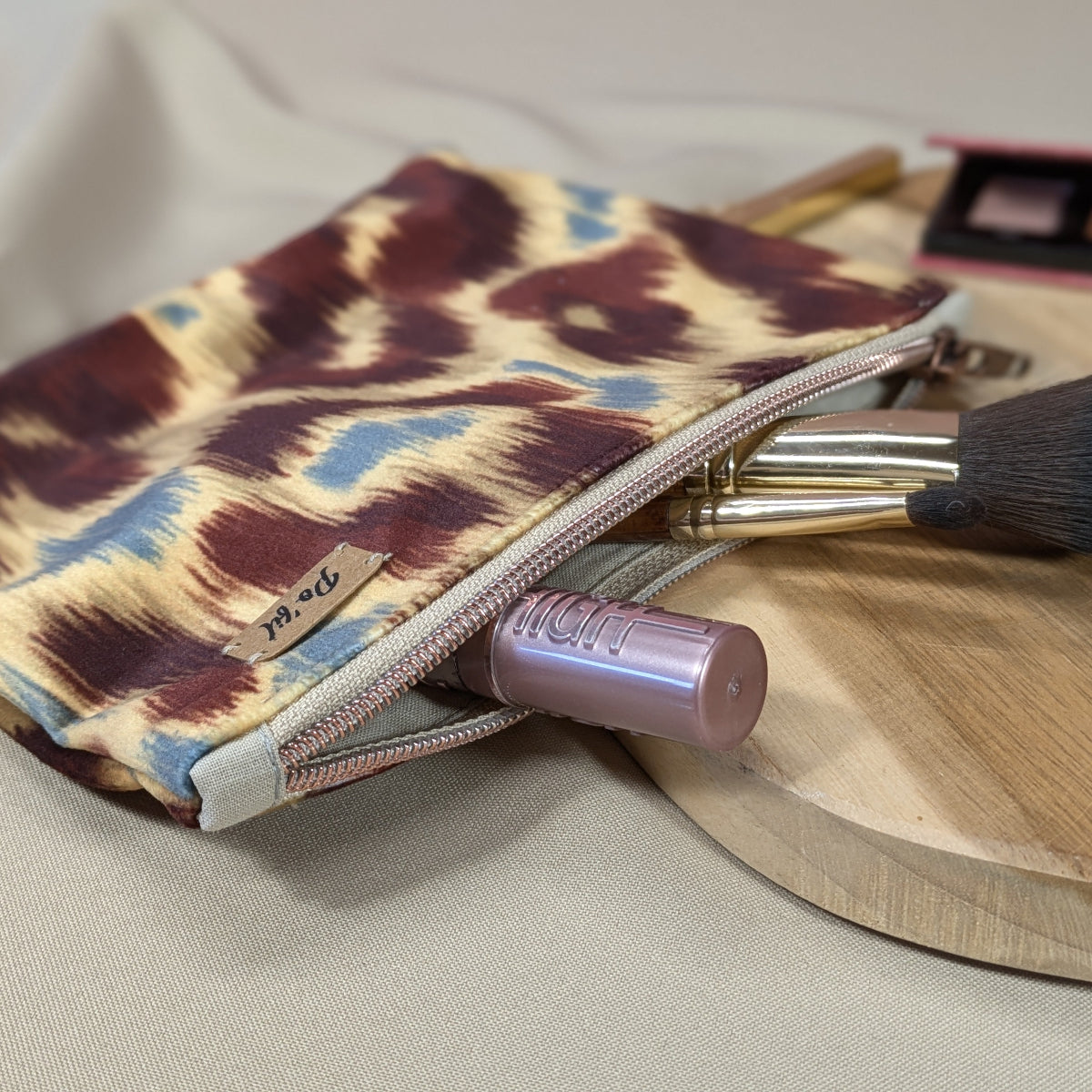 Zoom sur la fermeture cuivrée d'une pochette plate en velours ras