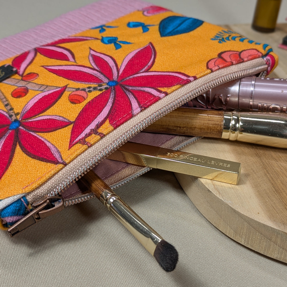 Zoom sur la fermeture cuivre d'une pochette plate en velours côtelé.
