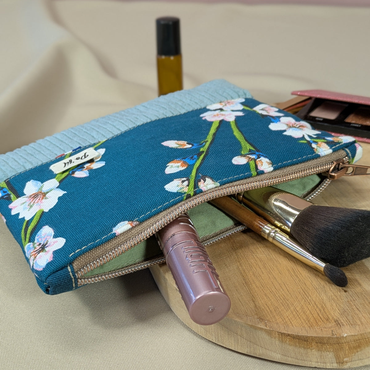 Zoom sur la fermeture cuivrée d'une pochette plate en velours côtelé et coton imprimé
