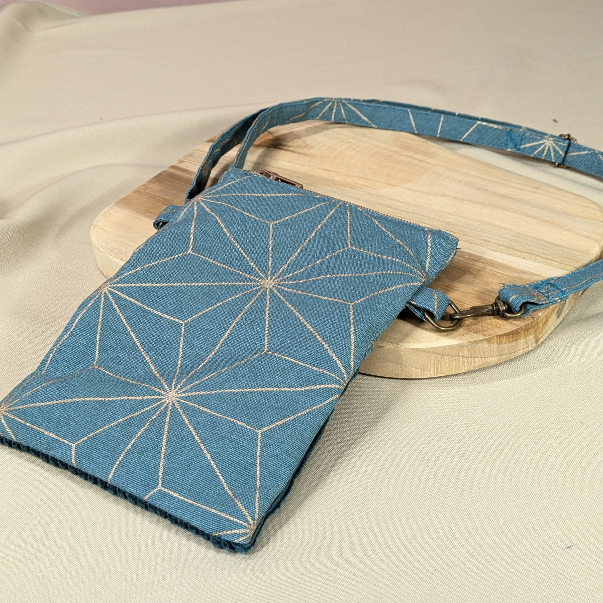 Dos de la pochette à téléphone en tissu  bleu canard imprimé d'étoiles géométriques dorées